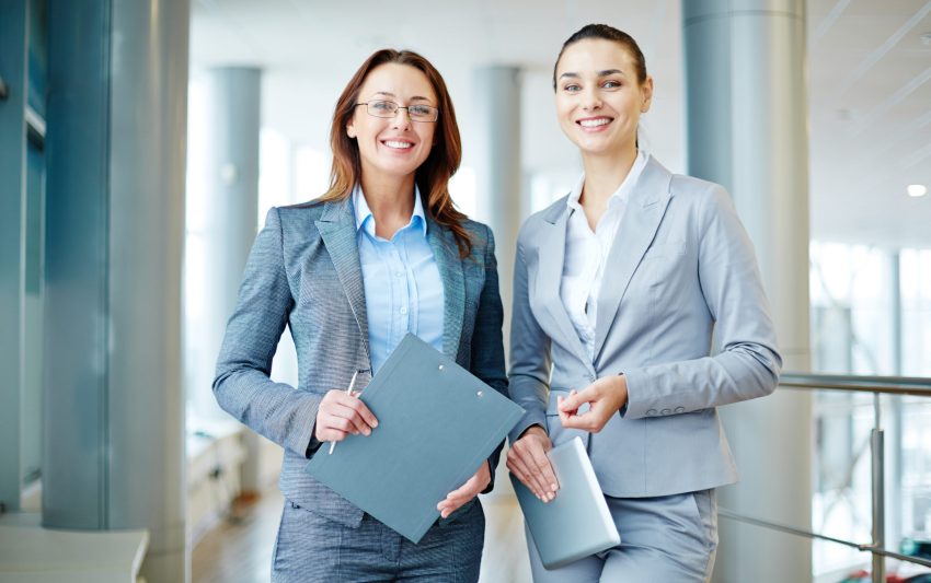 Smiling business colleagues standing with clipboard and touchpad